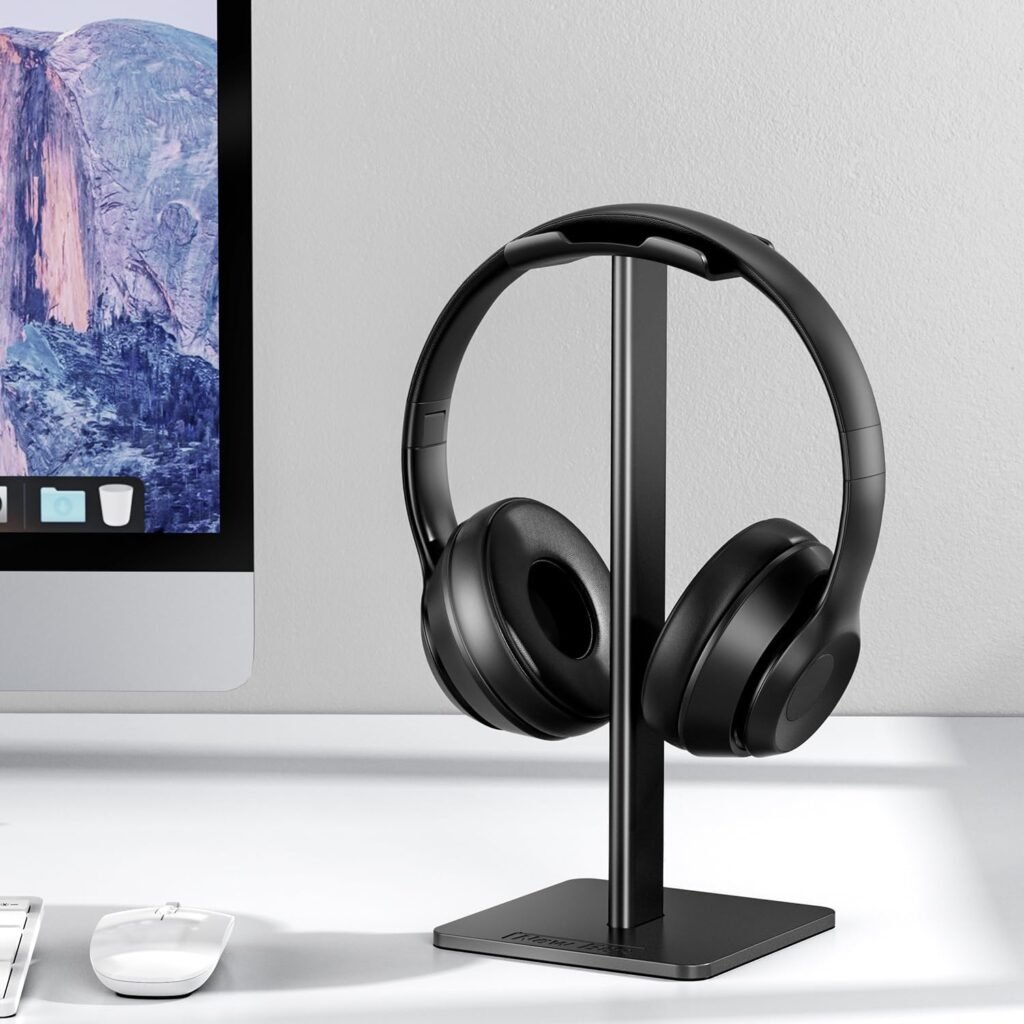 Auriculares sobre soporte moderno con ordenador y ratón en escritorio ordenado